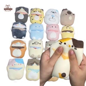 Può includere: Una collezione di giocattoli squishy a forma di gatto in vari design e colori, tra cui grigio, giallo, blu, rosa e marrone. Uno dei giocattoli viene schiacciato, mostrando la sua consistenza morbida. Il logo "MeowesomeCrafts" è in alto a sinistra.