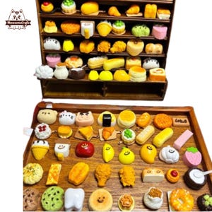 May include: A wooden display case and tray filled with miniature food items. The collection includes cakes, pastries, sushi, and other baked goods in various colours and shapes. The items are arranged on shelves and a wooden tray.