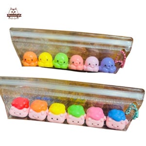 May include: Two clear plastic zipper bags each containing six colorful, small octopus-shaped charms. The top bag has orange, yellow, green, pink, light pink, and purple octopuses. The bottom bag has sushi-shaped charms with red, orange, yellow, green, pink, and blue toppings.