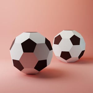 Könnte beinhalten: Zwei Fußbälle mit geometrischem Design. Die Bälle sind weiß mit schwarzen Fünfecken und vor einem weichen rosa Hintergrund. Die Bälle befinden sich im Vordergrund, einer leicht hinter dem anderen.