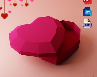 May include: A pink papercraft heart-shaped box with a lid open. The box is made of folded paper and has a geometric design. The box is on a pink background.