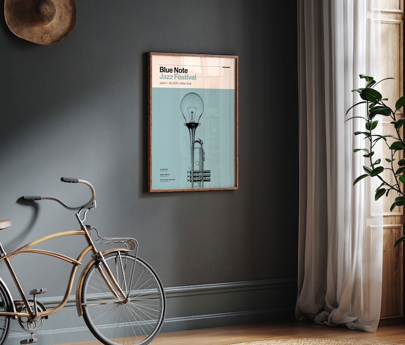 May include: A poster with a light blue background featuring a black and white illustration of a trumpet with a light bulb on top. The poster has the text "Blue Note Jazz Festival" and "June 1-30, 2023 - New York" printed on it.