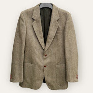 May include: A brown tweed blazer with a single-breasted button closure and two flap pockets. The blazer has a brown lining and a brown button.