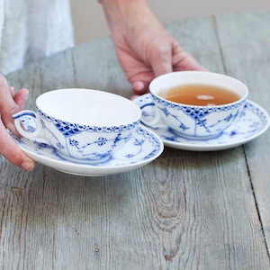 Puede incluir: Dos tazas de té azules y blancas con un patrón floral. Las tazas de té están llenas de té.