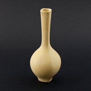 May include: A pale yellow ceramic vase with a rounded body and a long, slender neck.