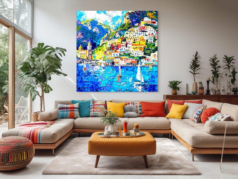 May include: A colorful painting of a seaside town with white sailboats in the water. The town is built on a hillside with colorful buildings and green trees. The sky is blue with white clouds.