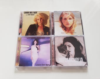 Peut inclure: Quatre albums CD de Lana Del Rey. Les pochettes d'album présentent des images de l'artiste, avec des titres tels que "Lana Del Rey", "Unreleased", "Melancholia" et "May Jailer Sirens."