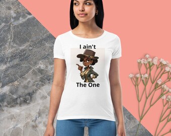 May include: White t-shirt with a cartoon illustration of a woman wearing a hat and pointing to the side. The text "I ain't The One" is printed on the shirt.