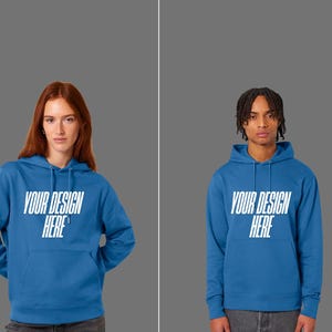 Peut inclure: Deux personnes portant des sweats à capuche bleus avec le texte "YOUR DESIGN HERE" en blanc. Les sweats à capuche ont une poche avant et une capuche à cordon. Le fond est de couleur grise unie.