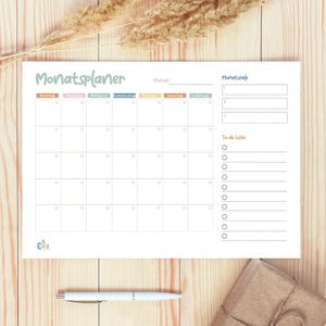 Peut inclure: Un planificateur mensuel blanc avec une grille de calendrier, une liste de choses à faire et un espace pour les objectifs mensuels. La grille du calendrier a les jours de la semaine étiquetés en allemand : Montag, Dienstag, Mittwoch, Donnerstag, Freitag, Samstag, Sonntag. Le mois est étiqueté "Mai".