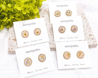 May include: Four cards with the text "moriyosha." on them. Each card has two small, round, gold-rimmed earrings with pressed flowers inside. The earrings are on a white background.