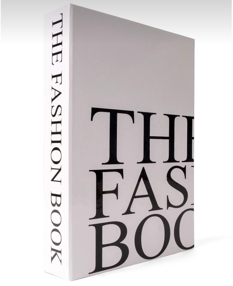 Peut inclure: Un livre blanc avec du texte noir qui dit "THE FASHION BOOK" sur le dos et "THE FASHION BOOK" sur la couverture.
