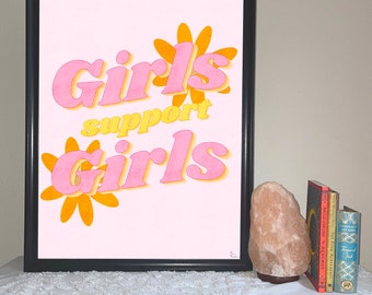 May include: A framed print with a pink background and yellow flowers. The print features the text "Girls support girls" in pink and yellow letters.