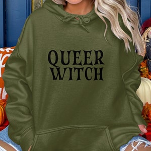 May include: A green hooded sweatshirt with the text "QUEER WITCH" in black lettering.
