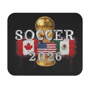 May include: Black mousepad featuring a gold soccer trophy with the word "SOCCER" above the flags of Canada, the United States, and Mexico. The number "2026" is below the trophy.