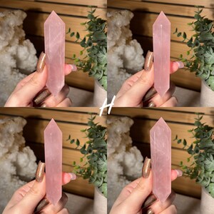 May include: Four images of a pink rose quartz crystal point. The crystal is held in a hand with a neutral background of plants and wood. The crystal is a pale pink color and has a pointed tip.