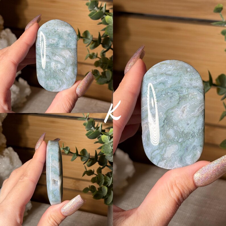 May include: A polished, oval-shaped stone with a light green and white marbled pattern. The stone has a smooth, rounded top and a flat bottom. The stone is held in a hand, showcasing its natural beauty and unique veining.