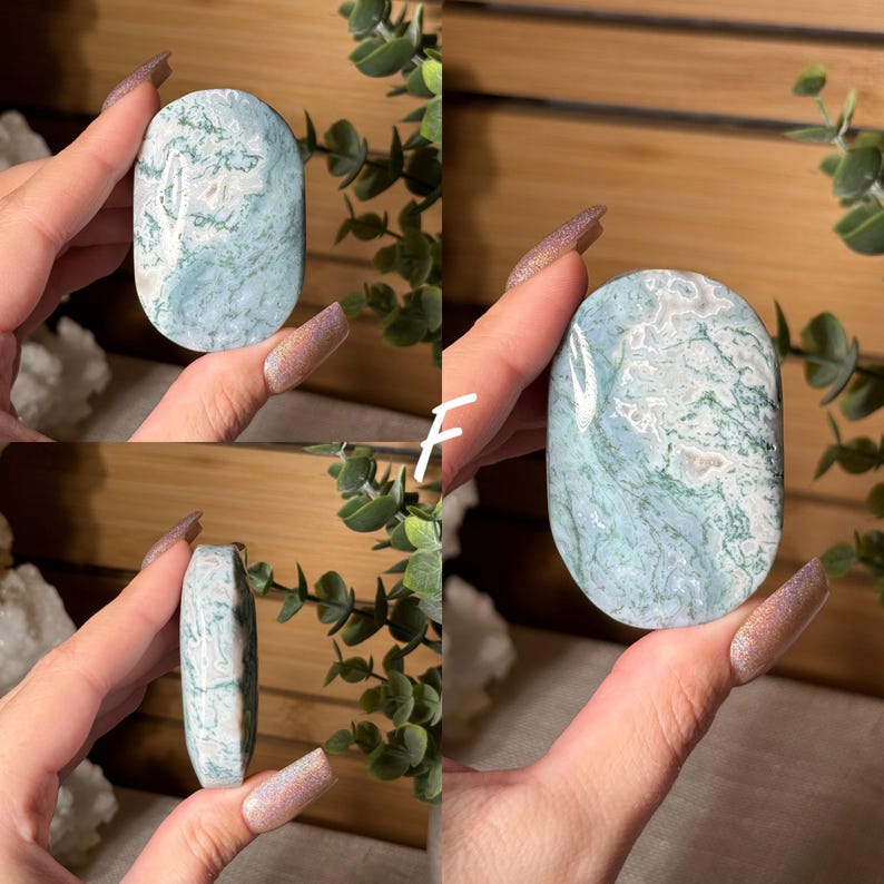 May include: Oval-shaped, polished gemstone with a light blue and white marbled pattern. The stone has a smooth, rounded shape and is held in a hand. The gemstone is a natural product and may vary slightly in color and pattern. The stone is approximately 3 inches long.