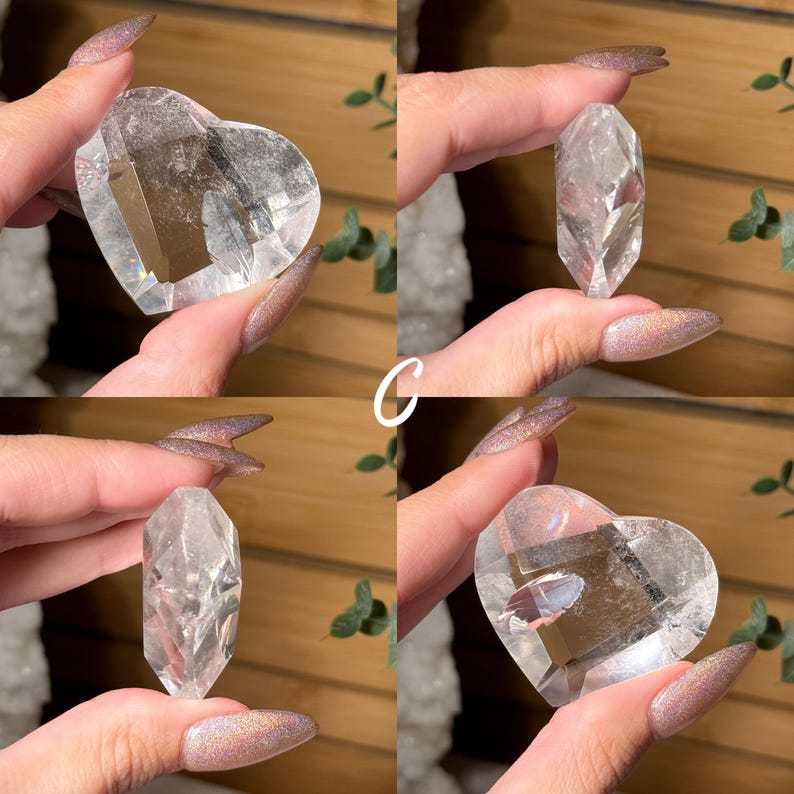 Puede incluir: Se muestran cuatro cristales de cuarzo transparente. Dos tienen forma de coraz&oacute;n y dos son puntas alargadas y facetadas. Los cristales se sostienen sobre un fondo natural, mostrando su claridad y forma. La letra "C" es visible.