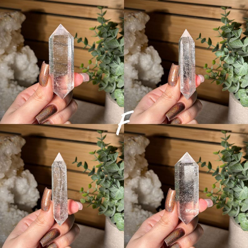 May include: Four clear quartz crystal points, each held in a hand. The crystals are transparent with visible internal structures. The background includes greenery and a wooden surface, suggesting a natural or spiritual theme.