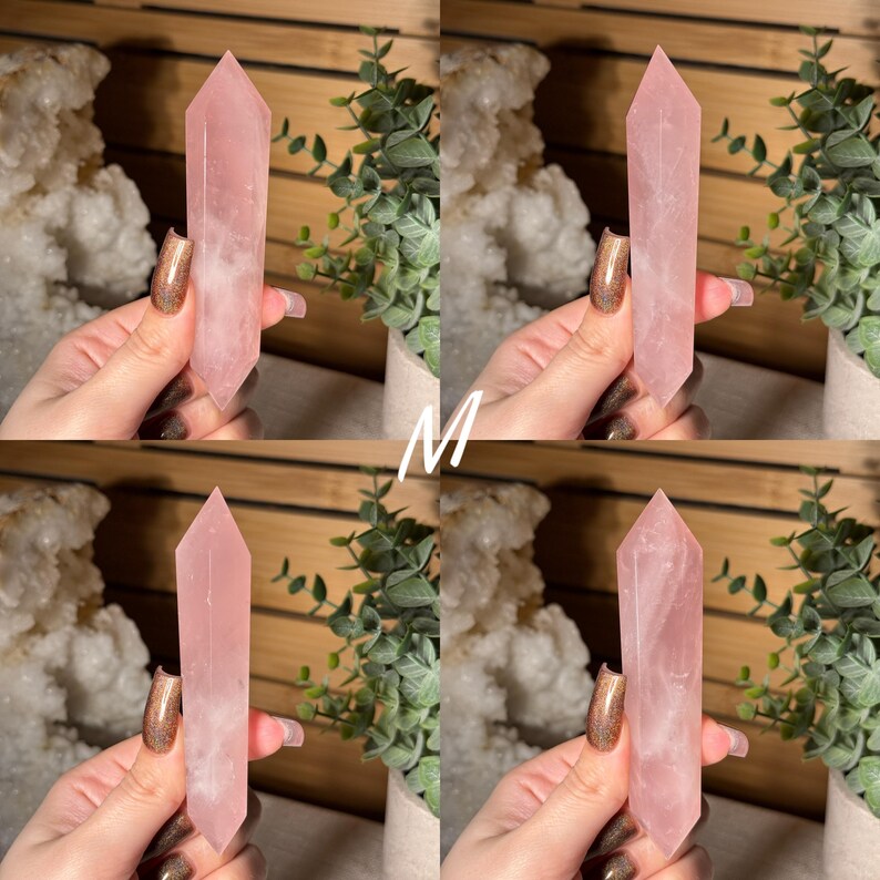 May include: Four rose quartz crystal obelisks, each held by a hand. The crystals are a soft pink color, with a polished, smooth surface. The obelisks are displayed against a backdrop of greenery and a wooden surface.