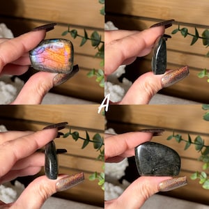 May include: Four polished gemstone specimens are displayed. One is a rectangular shape with iridescent orange, pink, and purple hues. The other three are dark, with a polished, reflective surface. The letter "A" is visible in the image.