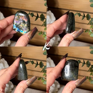 May include: Four polished labradorite stones in various shapes are displayed. The stones exhibit a range of colors, including blues, greens, and purples, with iridescent flashes. The stones are held in hands, showcasing their natural beauty and unique patterns.
