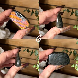 May include: Four polished gemstones are displayed. One is a rectangular shape with iridescent orange and purple hues. The other three are dark gray with varying shapes. The letter "G" is written in white cursive in the center of the image.