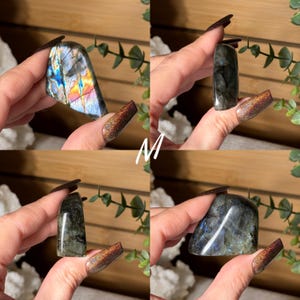 May include: Four polished labradorite crystals are displayed, each held in a hand. The stones vary in shape and size, showcasing iridescent flashes of blue, green, and yellow. The letter "M" is visible in the center of the image.