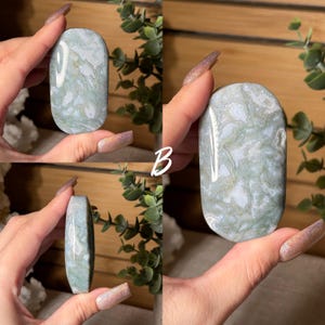 May include: A polished, oval-shaped stone with a marbled pattern of pale green and white. The stone is held in a hand, showcasing its smooth surface and natural variations. The stone's edges are rounded, and the overall aesthetic is organic and calming.