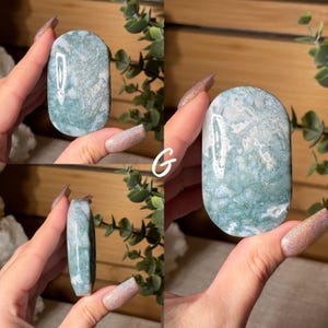 May include: A polished, oval-shaped gemstone with a marbled pattern of white and seafoam green. The stone is held in a hand, showcasing its smooth surface and natural variations. The letter "G" is visible in the image.