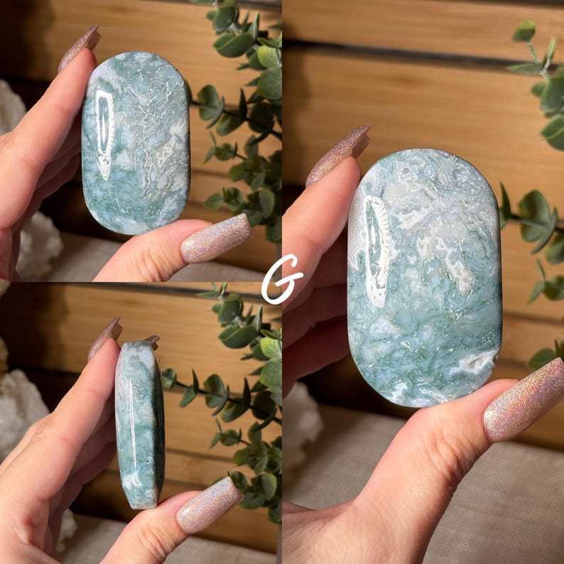 May include: A polished, oval-shaped gemstone with a marbled pattern of white and seafoam green. The stone is held in a hand, showcasing its smooth surface and natural variations. The letter "G" is visible in the image.