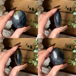 May include: Four images of polished blue tiger's eye stones. The stones are held in a hand, showcasing their oval and elongated shapes. The stones have a mix of blue, gold, and black colors, with a polished, reflective surface.