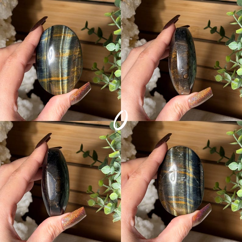 May include: Four polished oval-shaped gemstones with varying colors of blue, gold, and brown. The stones are held in hands, showcasing their smooth, reflective surfaces. The gemstones are displayed against a backdrop of greenery and wood.