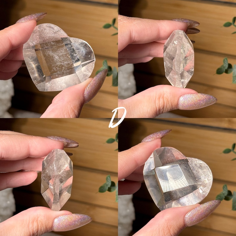 Puede incluir: Cuatro piezas de cristal de cuarzo transparente. Dos tienen forma de coraz&oacute;n y dos son cristales facetados puntiagudos. Los cristales se sostienen contra un fondo de madera. La letra "D" est&aacute; escrita en blanco en la imagen.