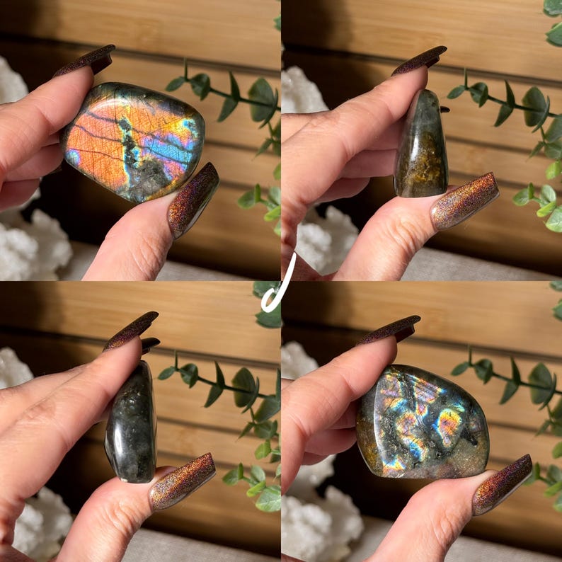 May include: Four polished labradorite stones in various shapes and sizes. The stones display iridescent flashes of blue, orange, and green. The background includes greenery and a wooden surface, enhancing the natural aesthetic of the gemstones.