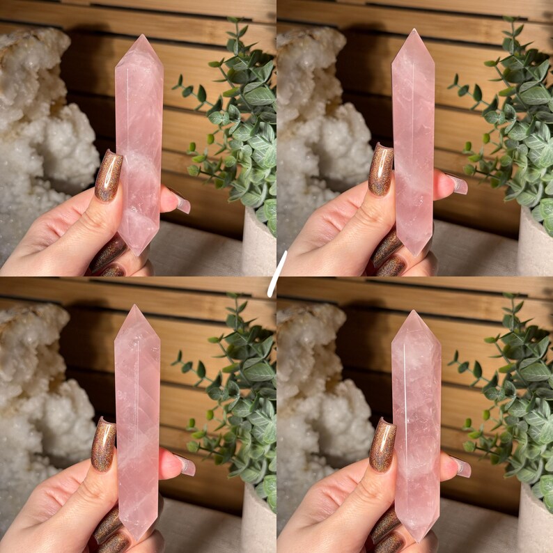 May include: Four rose quartz crystal points, each held by a hand. The crystals are a soft pink color and have a pointed, elongated shape. The background includes greenery and a white, textured object.
