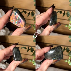 May include: Four images of polished labradorite crystals. The crystals vary in shape and size, displaying a range of colors including iridescent blues, oranges, and greens. The stones are held up against a neutral background, showcasing their natural beauty and unique patterns.