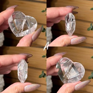 Puede incluir: Cuatro piezas de cristal de cuarzo transparente. Dos tienen forma de coraz&oacute;n y dos son puntiagudas. Los cristales se sostienen sobre un fondo de madera. La letra "A" est&aacute; escrita en blanco en la imagen.