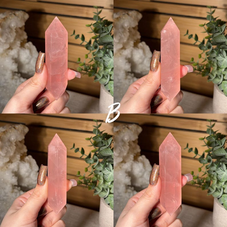 May include: Four rose quartz crystal points, each with a polished, faceted design. The crystals are a soft pink color and are held up against a wooden background with greenery and a white crystal formation. The letter "B" is in the center.