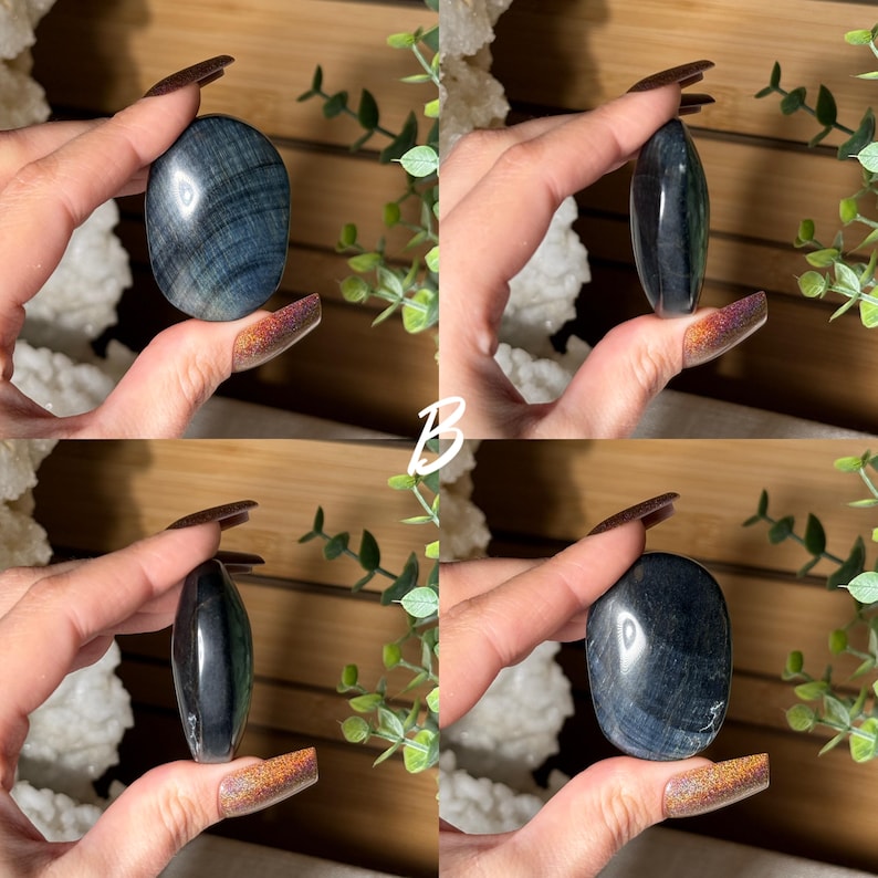 May include: Four images of polished blue tiger eye stones. The stones are oval-shaped and held in a hand. The stones have a chatoyant effect, with bands of color that shimmer in the light. The background includes greenery and a wooden surface.