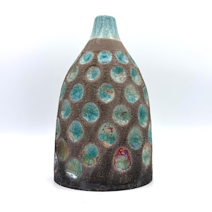 May include: A ceramic vase with a tapered neck and a textured, dark brown exterior featuring a repeating pattern of circular indentations. Each indentation is filled with a glossy, crackled turquoise glaze, with some areas showing hints of red and orange.
