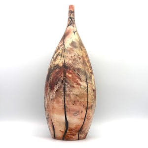 May include: A tall, slender, teardrop-shaped vase with a narrow neck and a wide, rounded base. The surface features a mottled, earthy color palette of cream, tan, and reddish-brown, accented by thin, dark, vertical lines running along the body.