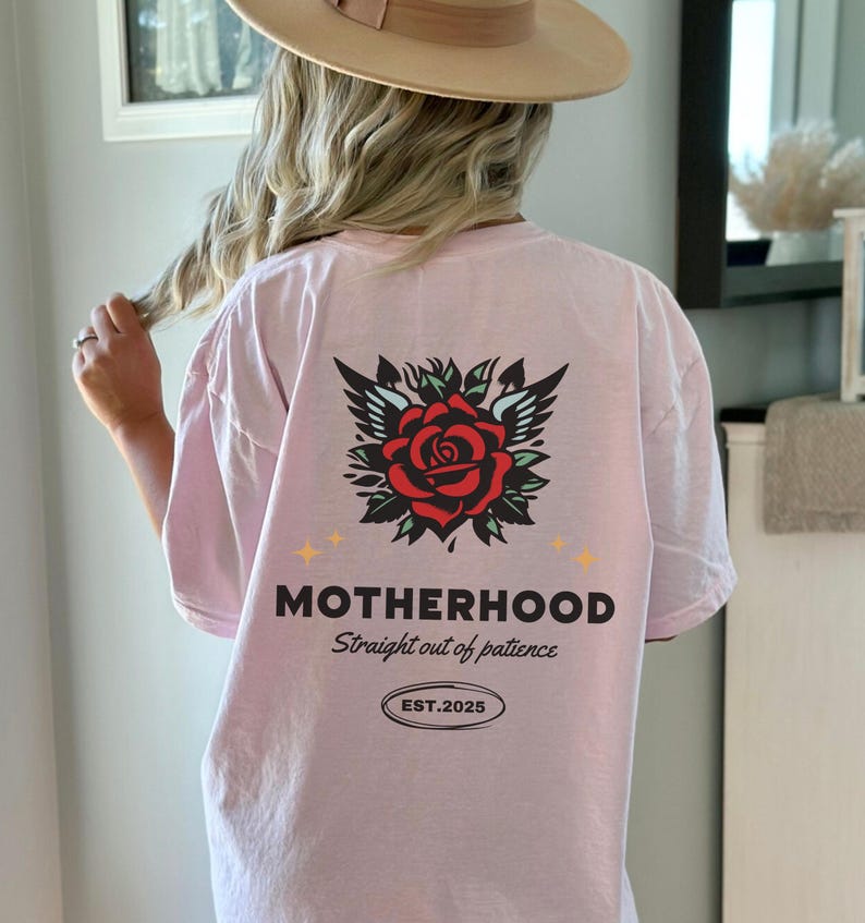 May include: Pink t-shirt with a rose and wings graphic and the text "MOTHERHOOD Straight out of patience EST. 2025"