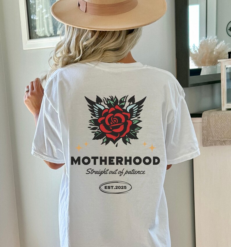 May include: White t-shirt with a red rose and wings graphic on the back. The text "MOTHERHOOD straight out of patience EST. 2025" is printed below the graphic.