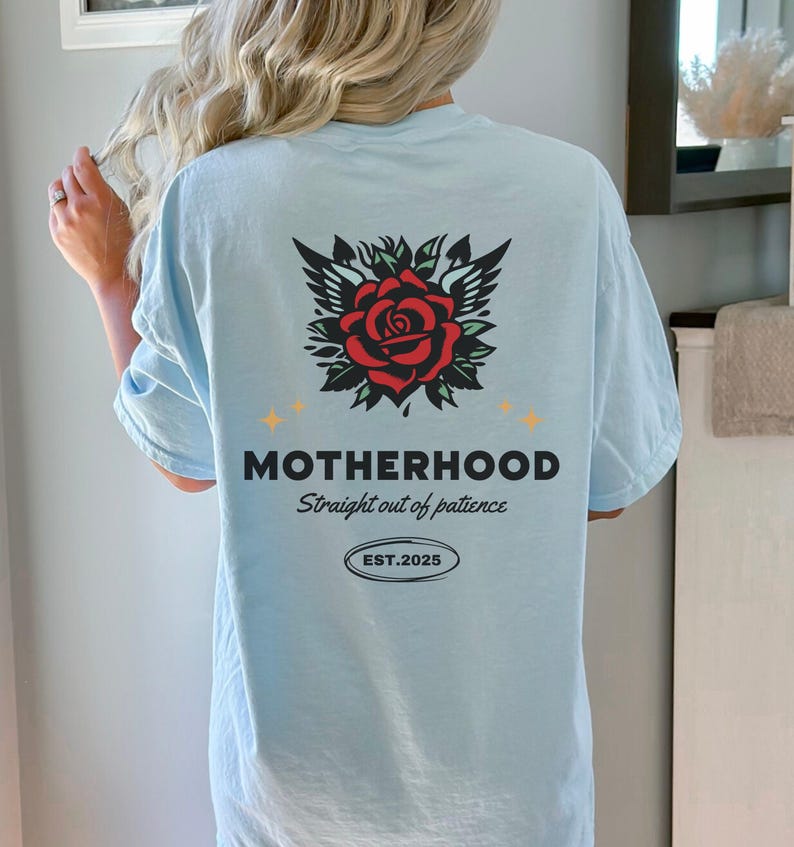 May include: Light blue t-shirt with a red rose with wings and the text "MOTHERHOOD Straight out of patience EST. 2025"