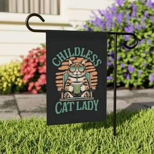 May include: A black garden flag with a cartoon cat wearing sunglasses and holding a coconut drink. The text on the flag reads "Childless Cat Lady".
