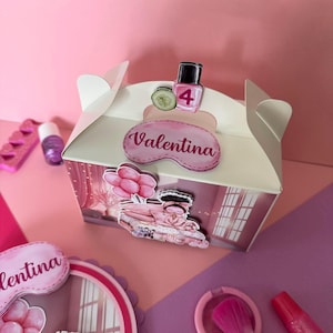 May include: A white gift box with a handle, decorated with pink accents and stickers. The stickers include a nail polish bottle, a cucumber slice, and the name "Valentina". Other beauty-themed items are scattered around the box.