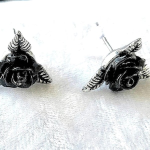 May include: A pair of black rose stud earrings. Each earring features a detailed rose with leaves, crafted in a silver-tone metal. The earrings are designed with a post and backing for secure wear, perfect for adding a touch of floral elegance.