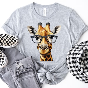 May include: A gray t-shirt with a graphic of a giraffe wearing glasses. The giraffe is brown and yellow with black spots. The glasses are black.